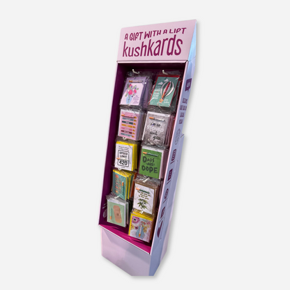 Fully stocked vertical five-tiered KushKards cardboard display stand with various humorous and themed greeting cards, prominently displayed with a magenta and white color scheme.