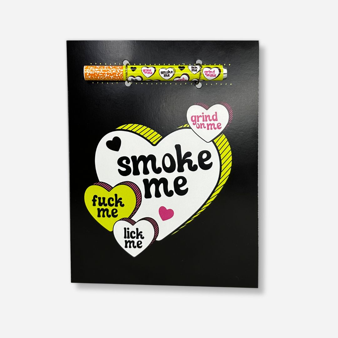 A bold black greeting card featuring a large white heart with playful yellow trim, surrounded by smaller hearts with flirtatious phrases like 'Smoke Me,' 'Grind on Me,' and 'Lick Me,' in a daring and humorous style.