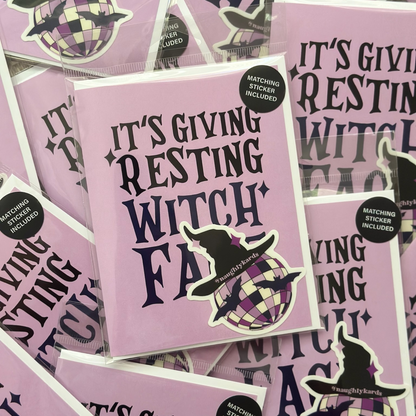 A greeting card with the phrase "It's Giving Resting Witch Face" in bold black letters, accompanied by a matching sticker featuring a purple and black checkered disco ball with a witch hat on top. The card is displayed among several identical cards in the background, all packaged with the matching sticker.